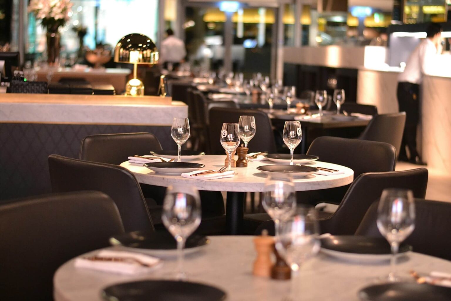 Tables rondes avec verres à l'intérieur d'un restaurant.